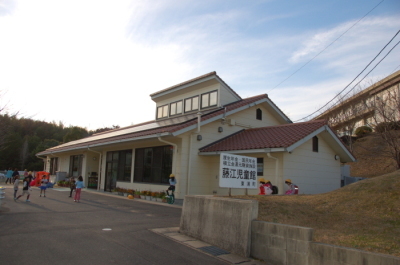 藤江児童館の建物を写した写真。建物の前の広場で複数の子供たちが遊んでいる様子が写っている。