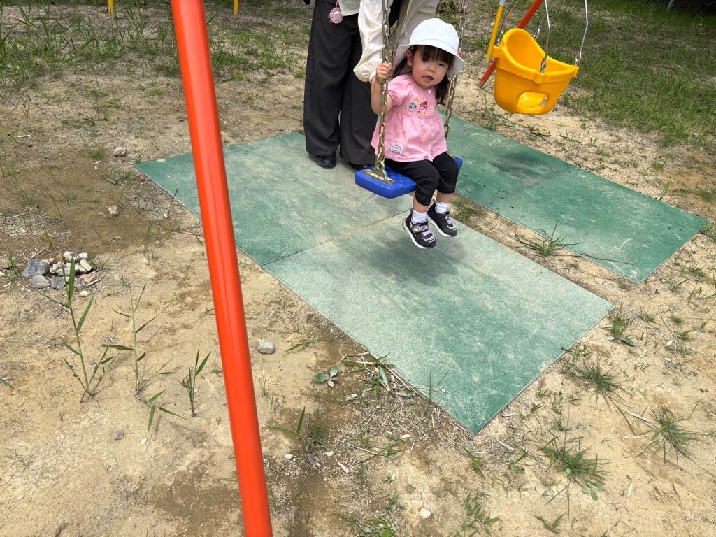 こあらの日、女の子が公園のブランコに乗っているところ