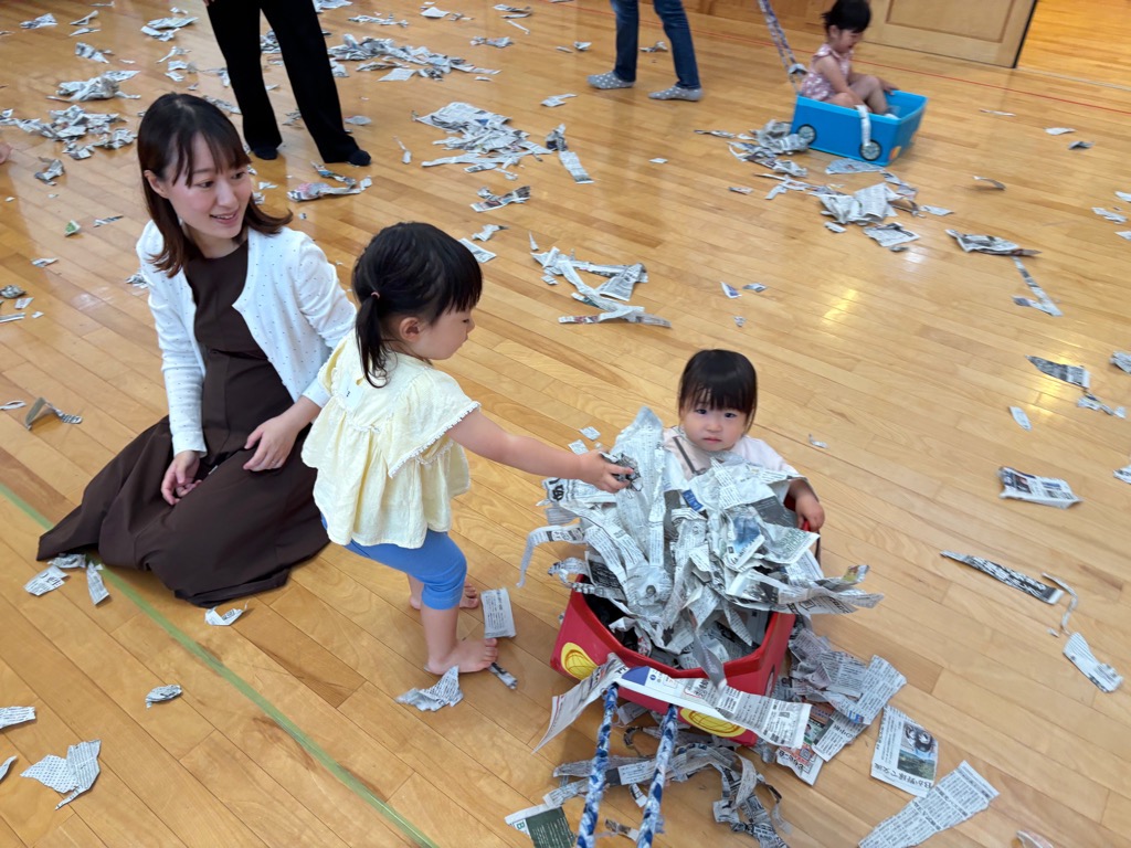 こあらの日の新聞紙あそび 箱車にのって新聞紙をいっぱい乗せてるところ