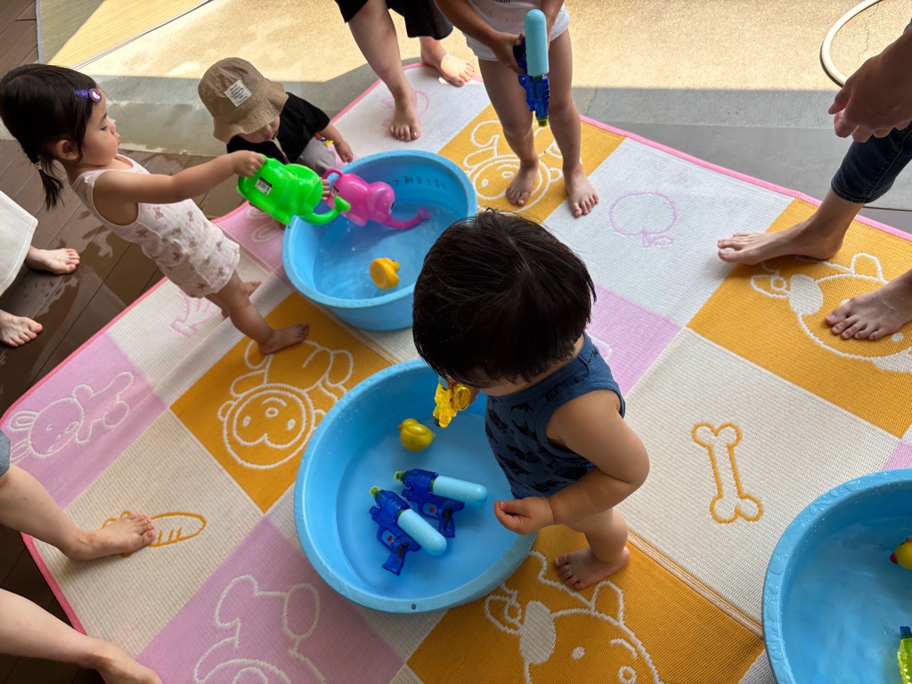 こあらの日の水遊び たらいの水に水鉄砲やぞうさんじょうろで水遊びしているところ