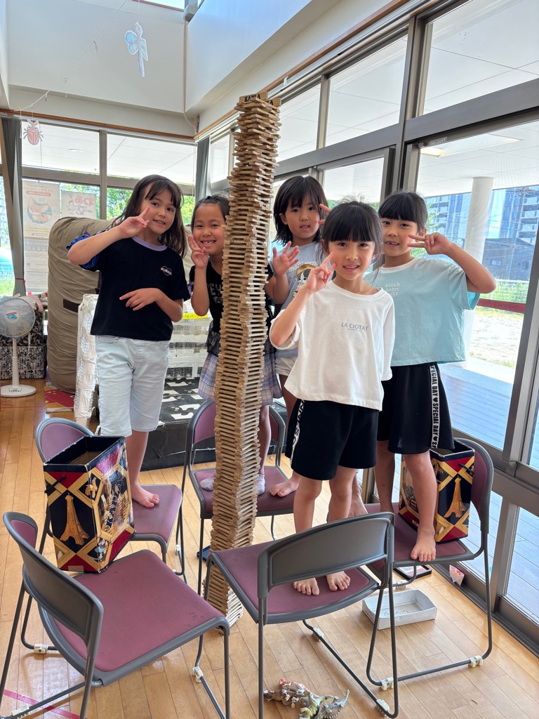 カプラタワーをつくってピースをしている女の子5人