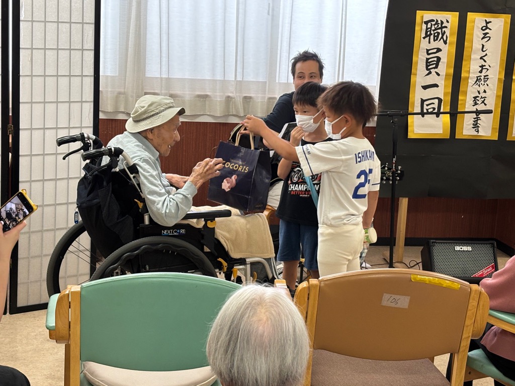 100歳を迎えたおじいちゃんに児童館で作ったプレゼントを渡しているところ