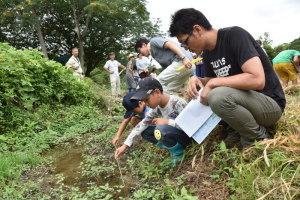 小川の水温を計る親子