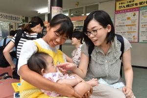お母さんと一緒に赤ちゃんをあやす中学生