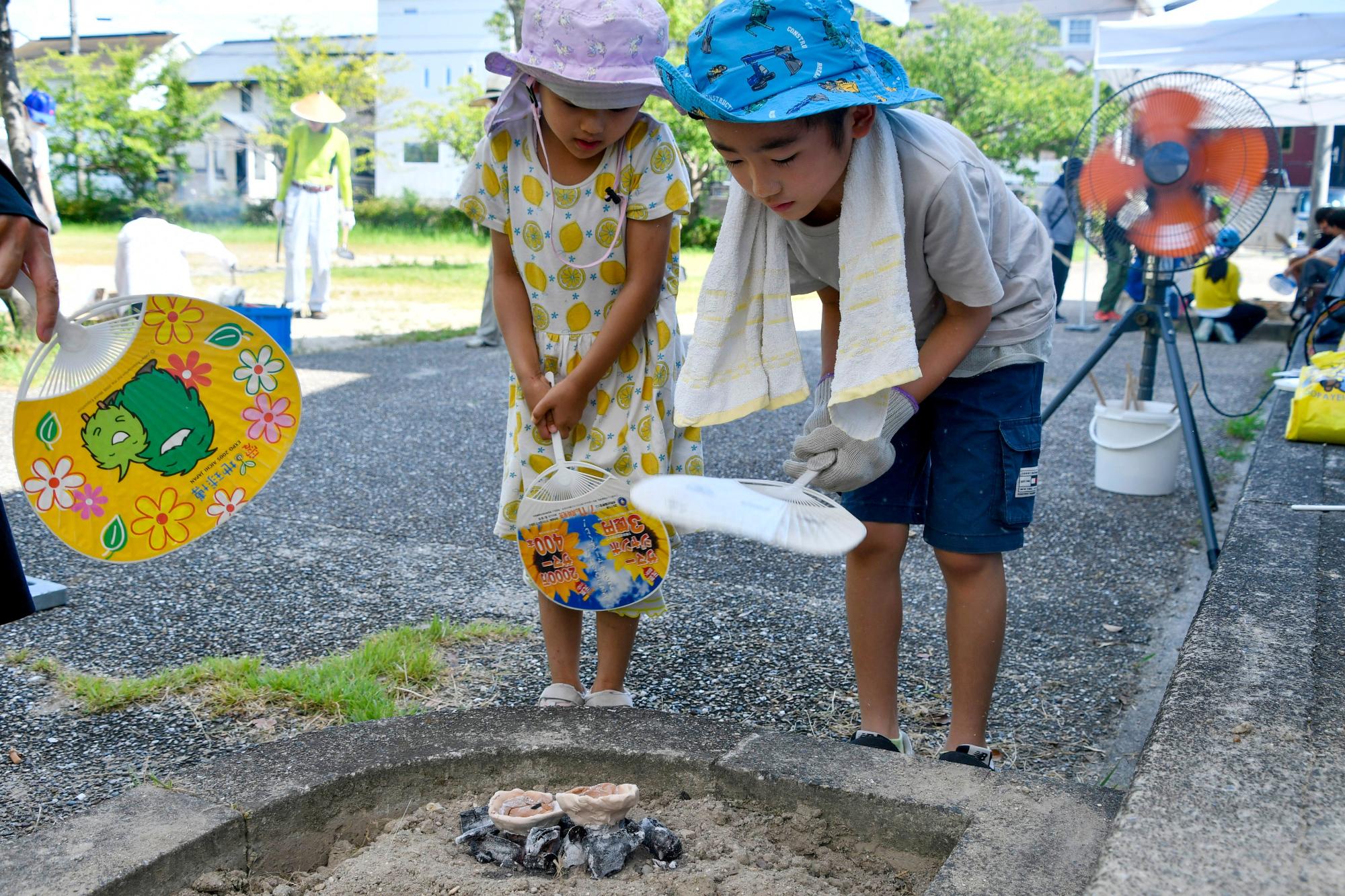 うちわで炭を仰ぎ製塩土器を温める子どもたち