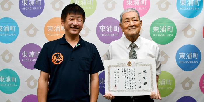 感謝状を手に、町長と笑みを浮かべる細川さん