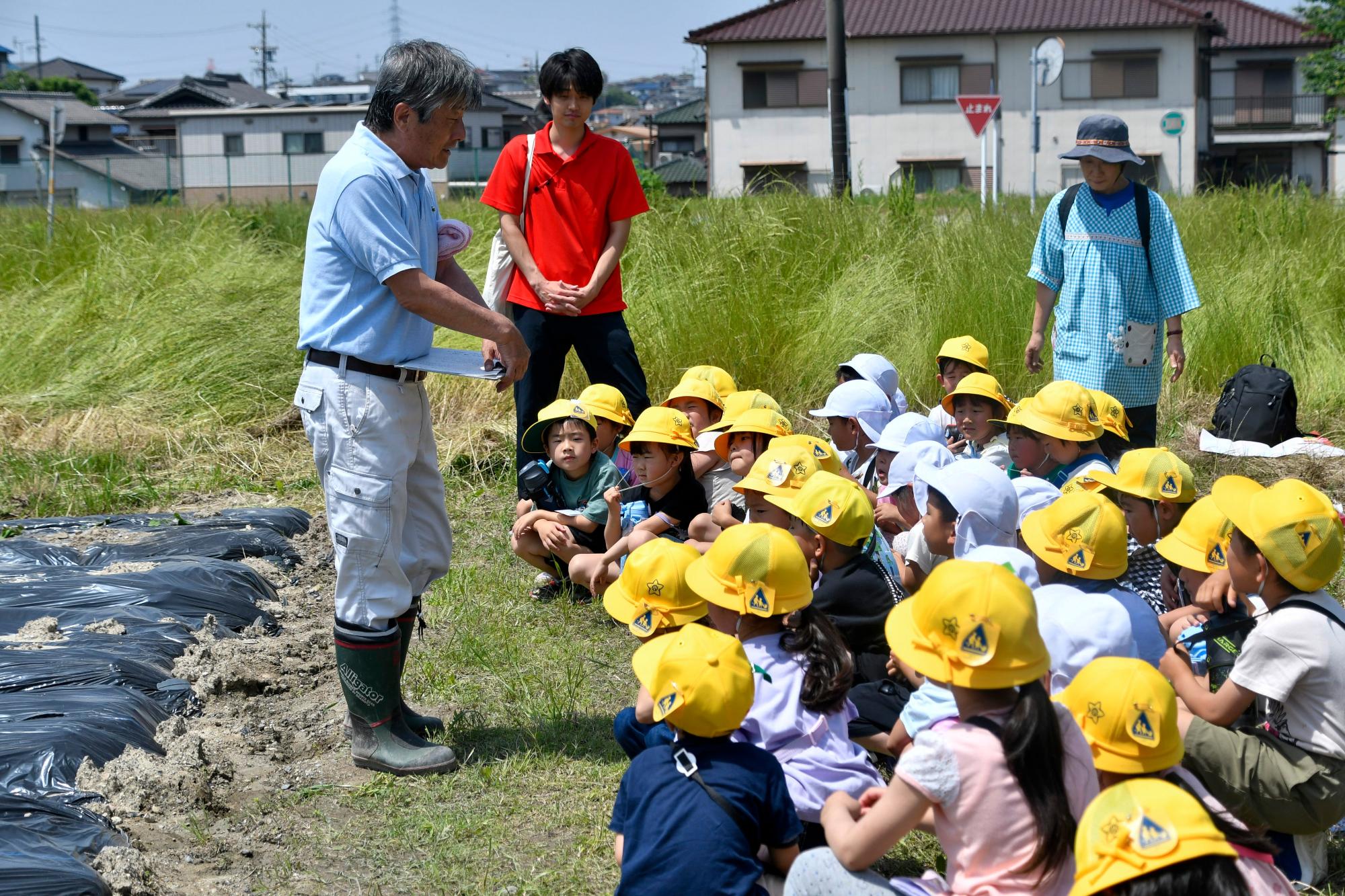 サツマイモ苗植えの説明を聞く児童と園児たち