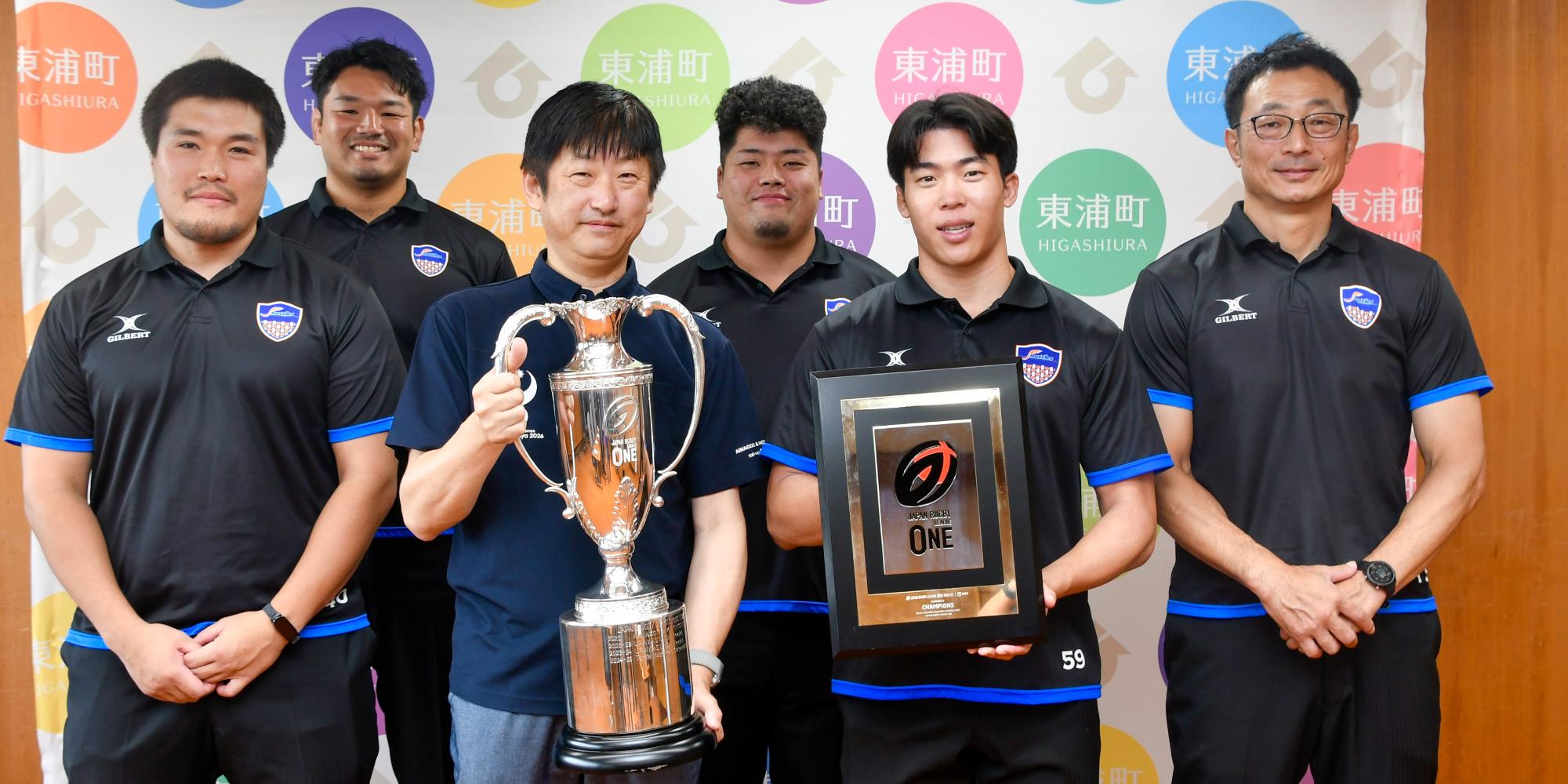 優勝トロフィーを手にする日高町長と豊田自動織機シャトルズ愛知の選手たち