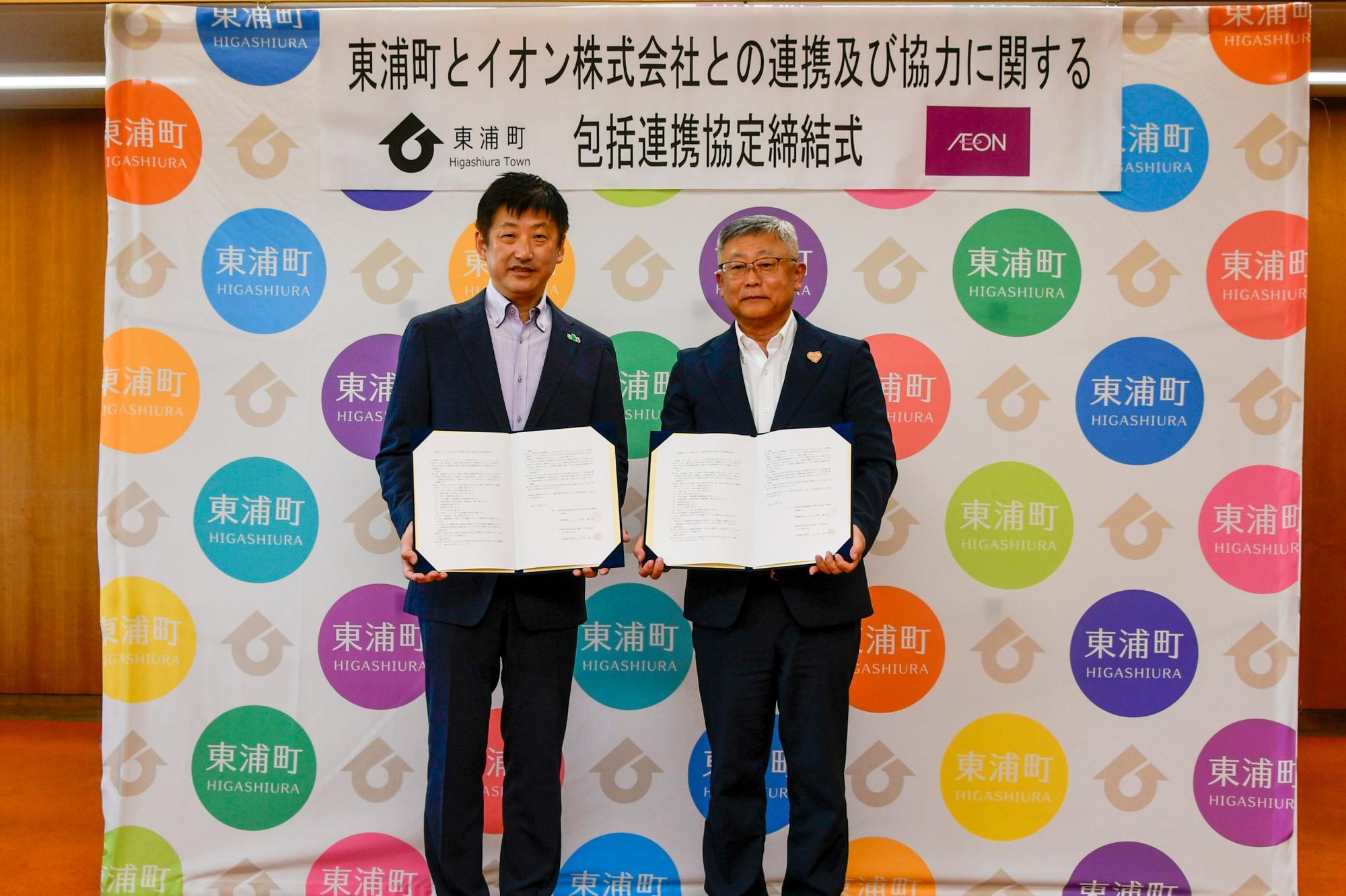 協定書を手に撮影する町長と山本氏