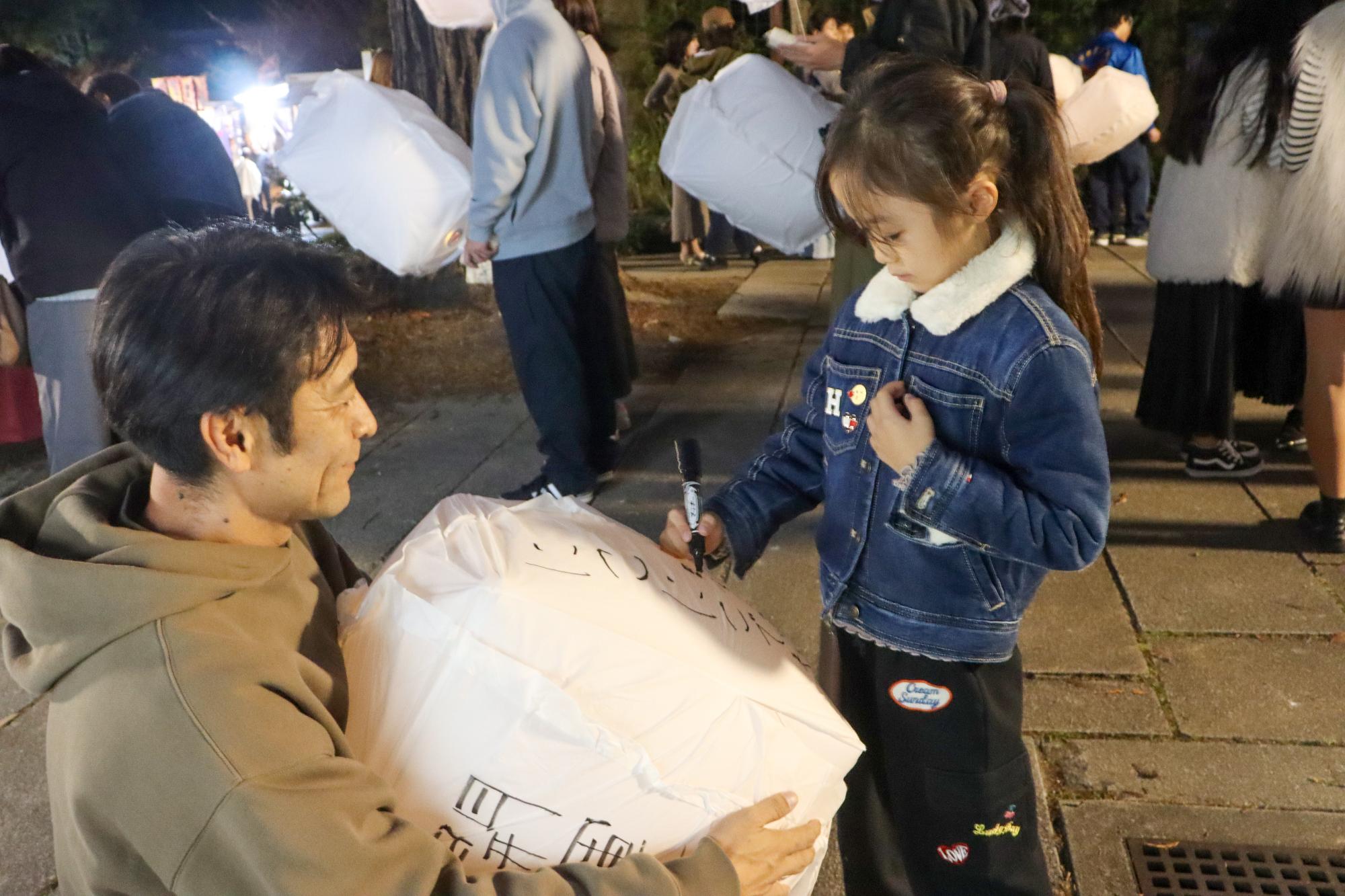 ランタンに願い事を書く親子