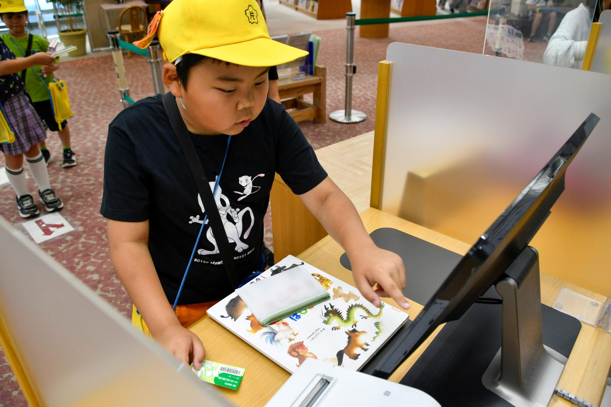 貸出機を使った手続きをする児童