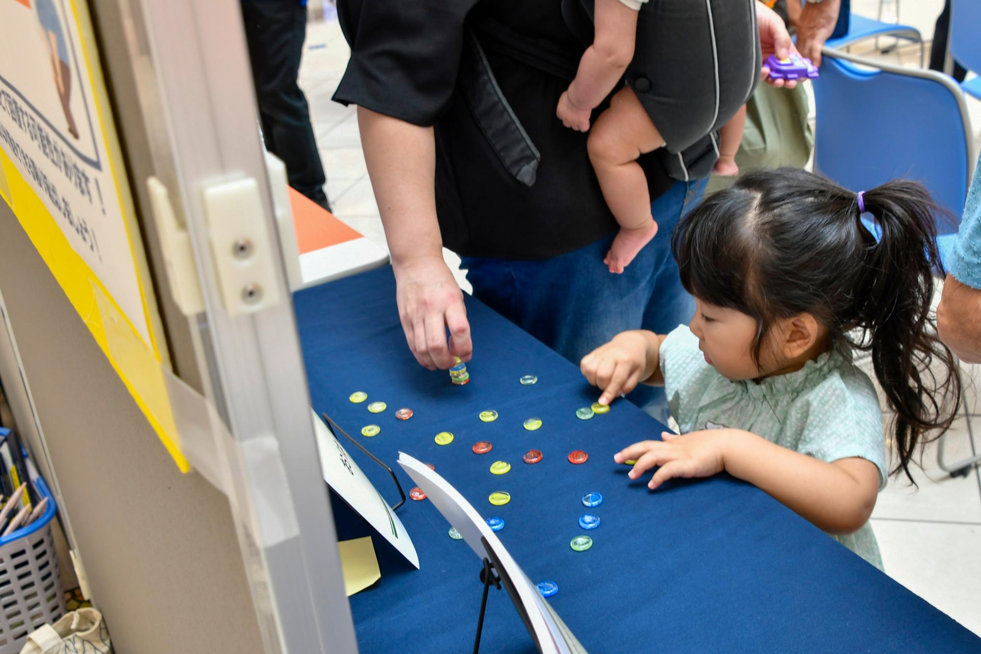 昔遊び体験コーナーでおはじきに触れる子ども