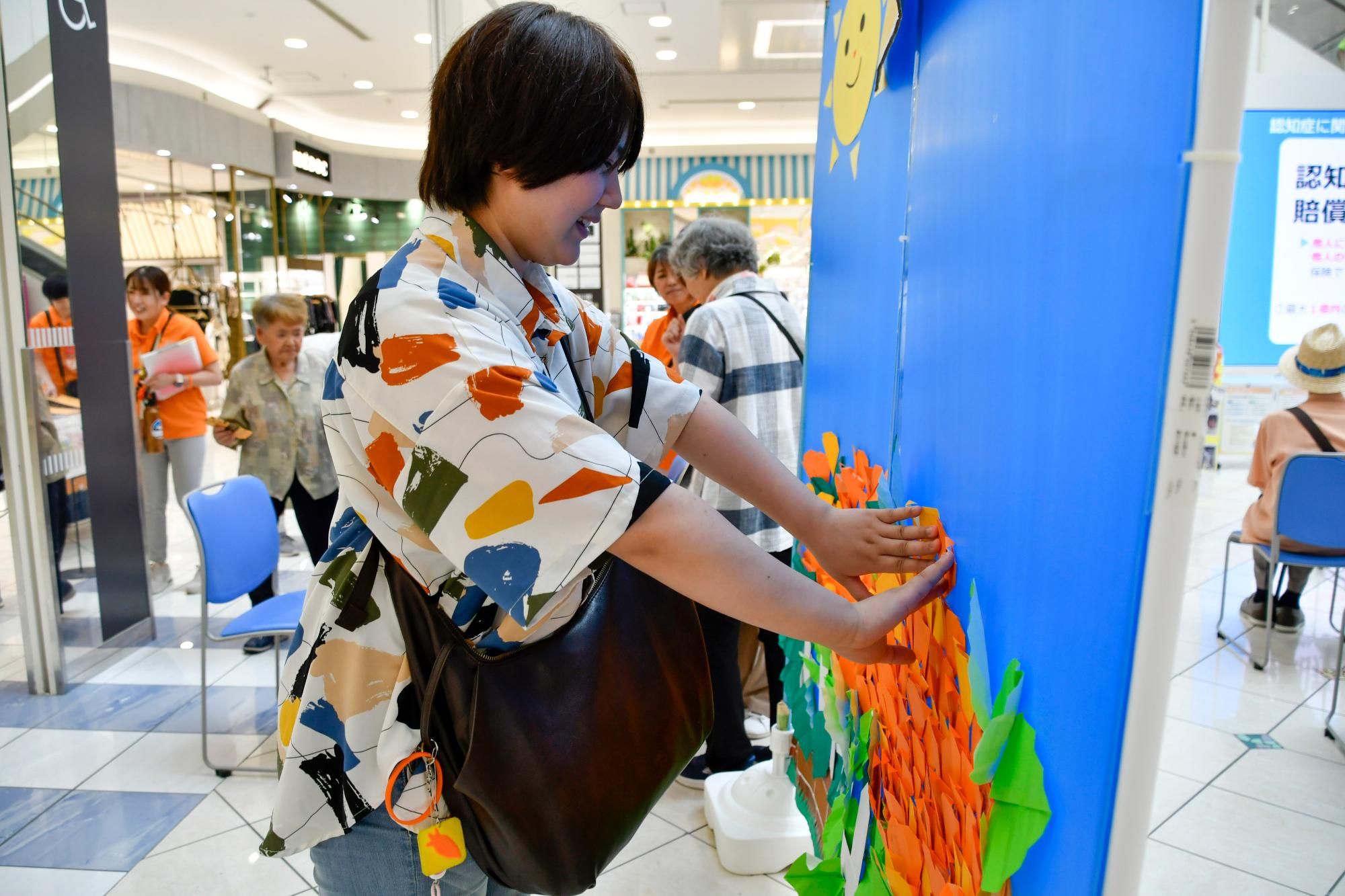 オレンジフラワーアートにメッセージを添える人