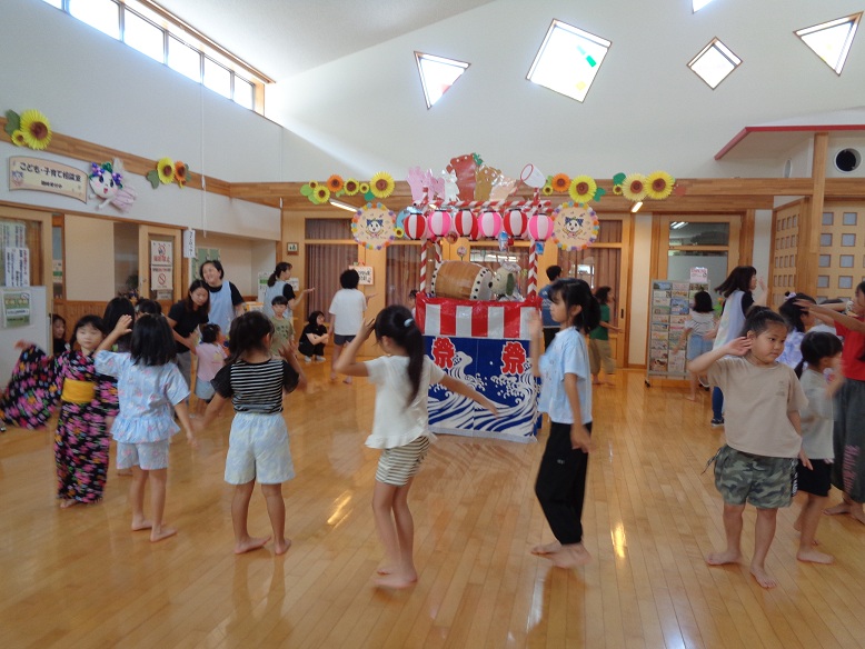 手作り矢倉を囲んでこどもたちが盆踊りを踊っているところ