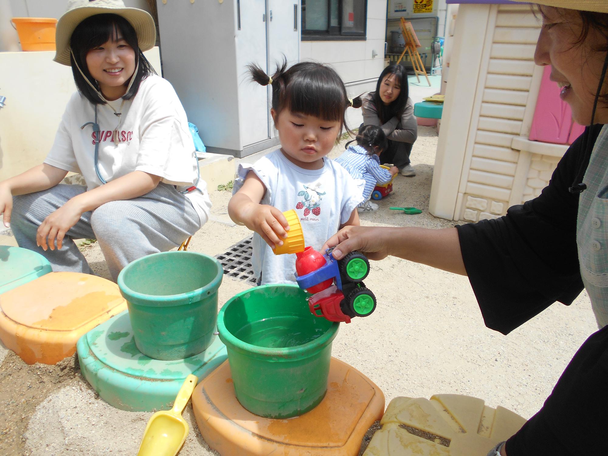こどもが先生とおもちゃと水で遊んでいる