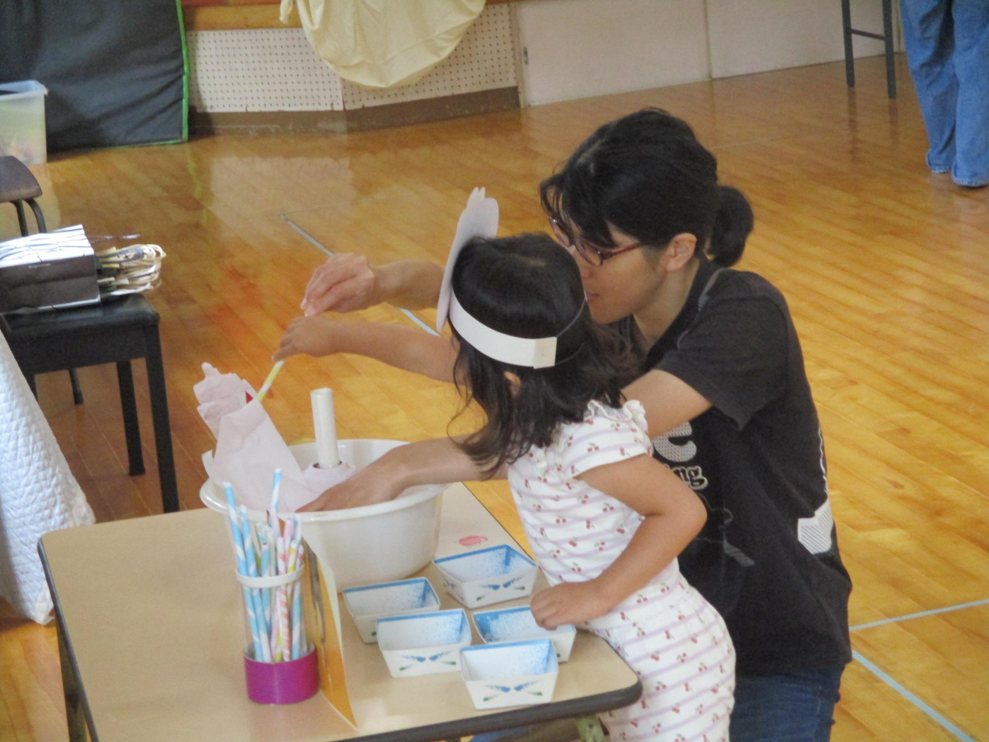 綿菓子作りごっこをする親子