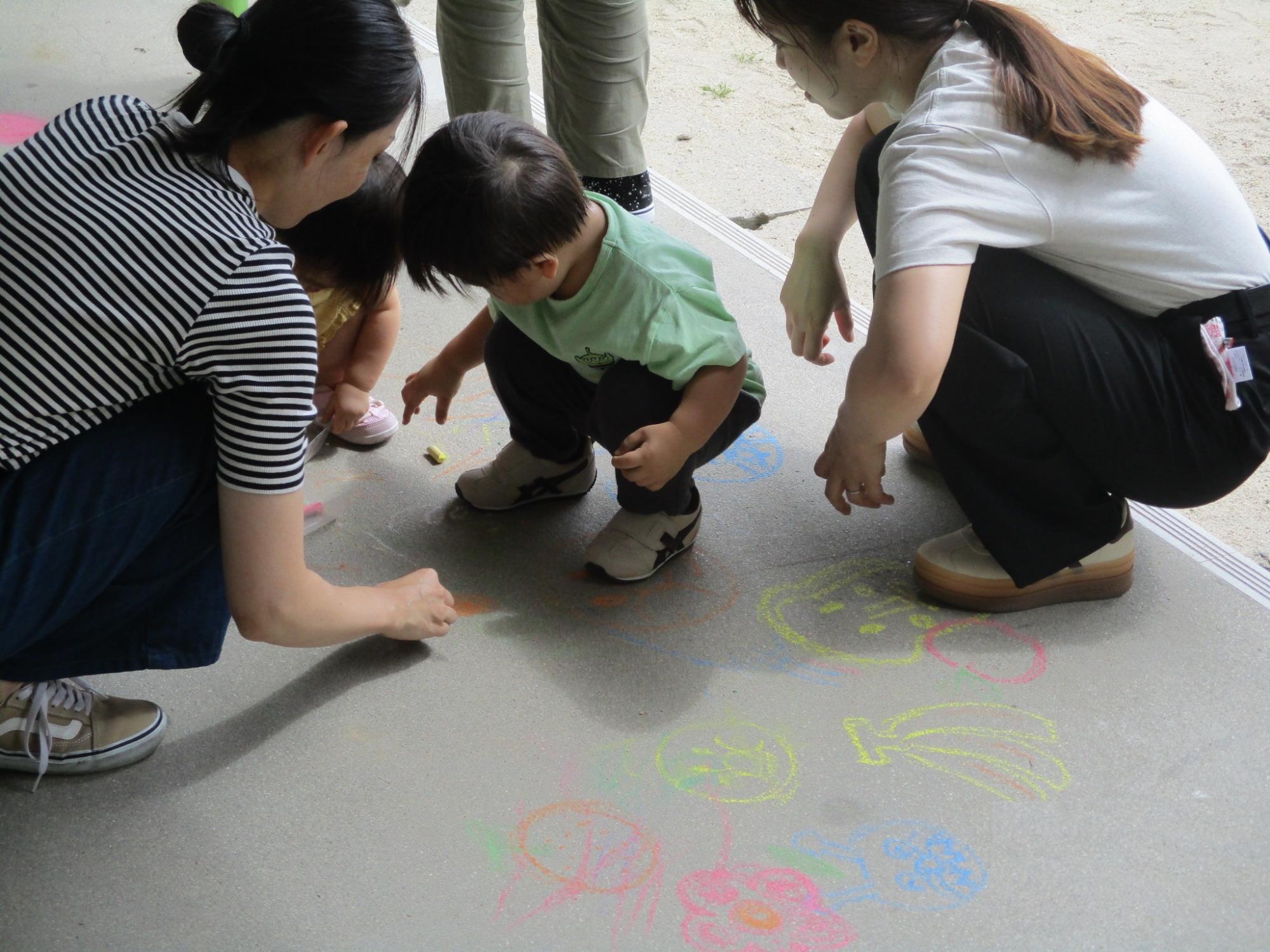 チョークで落書きあそびをする子たち