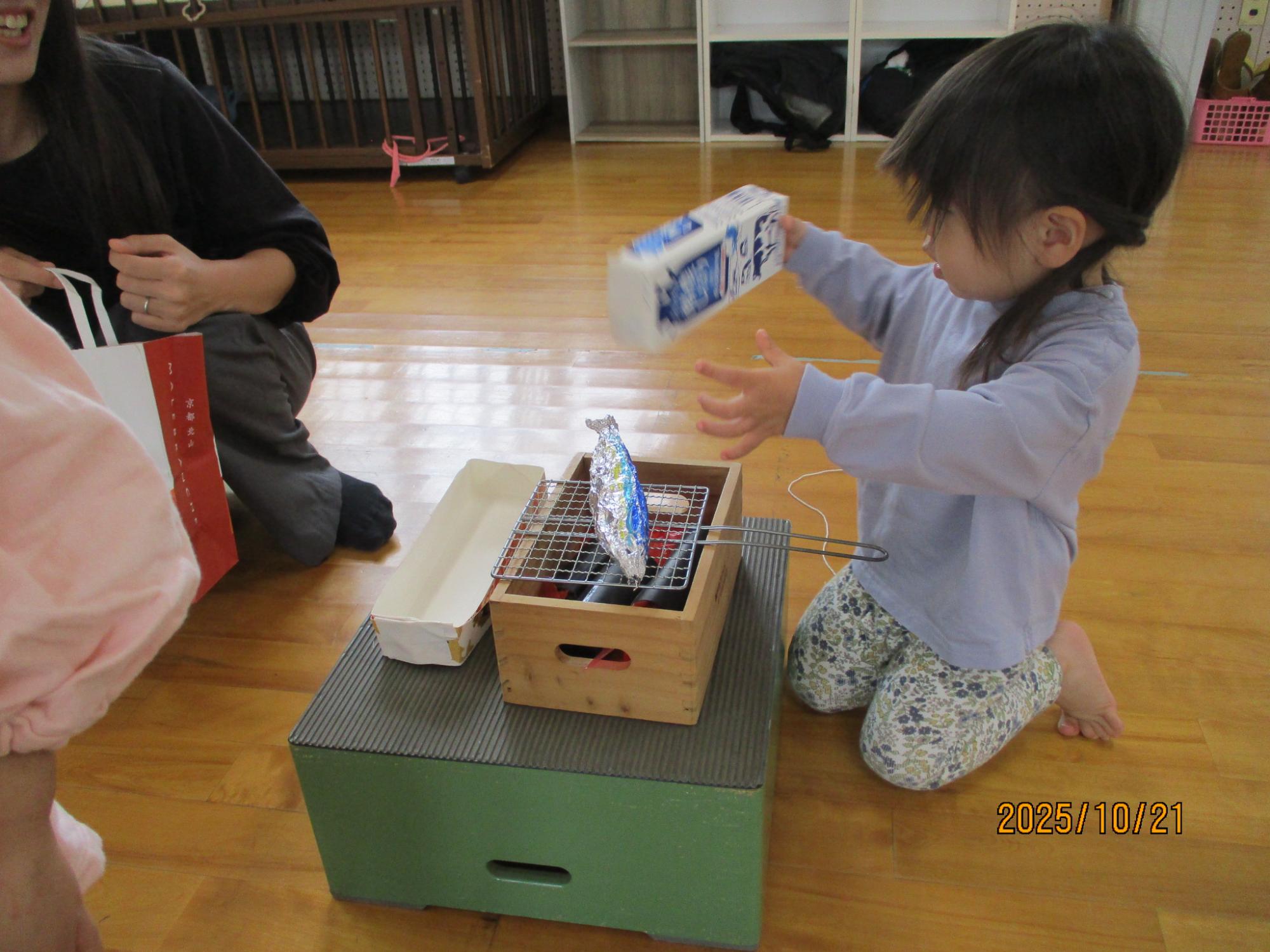 サンマを焼く真似をする子