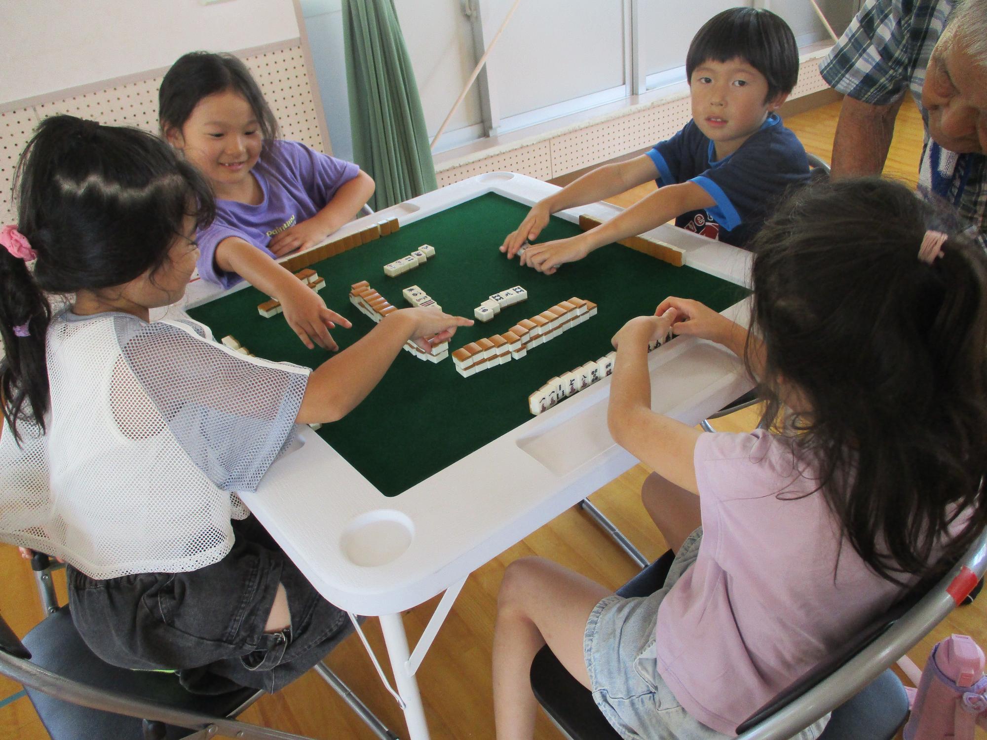 教えてもらいながら麻雀をやってみる子たち