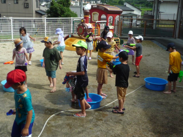 屋外ひろばで水遊びを楽しんでいる子どもたち