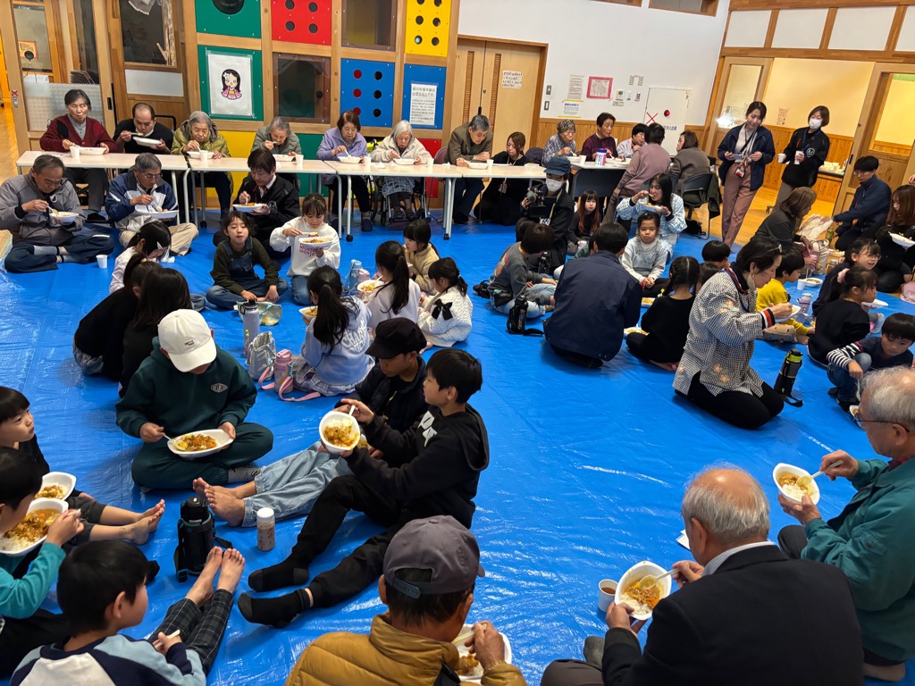 石浜西児童館の遊戯室で老人クラブの方、敬愛苑入居者さん、こどもたち、親子みんなで地域食堂パレットさんが作ってくれたカレーライスを食べてるところ