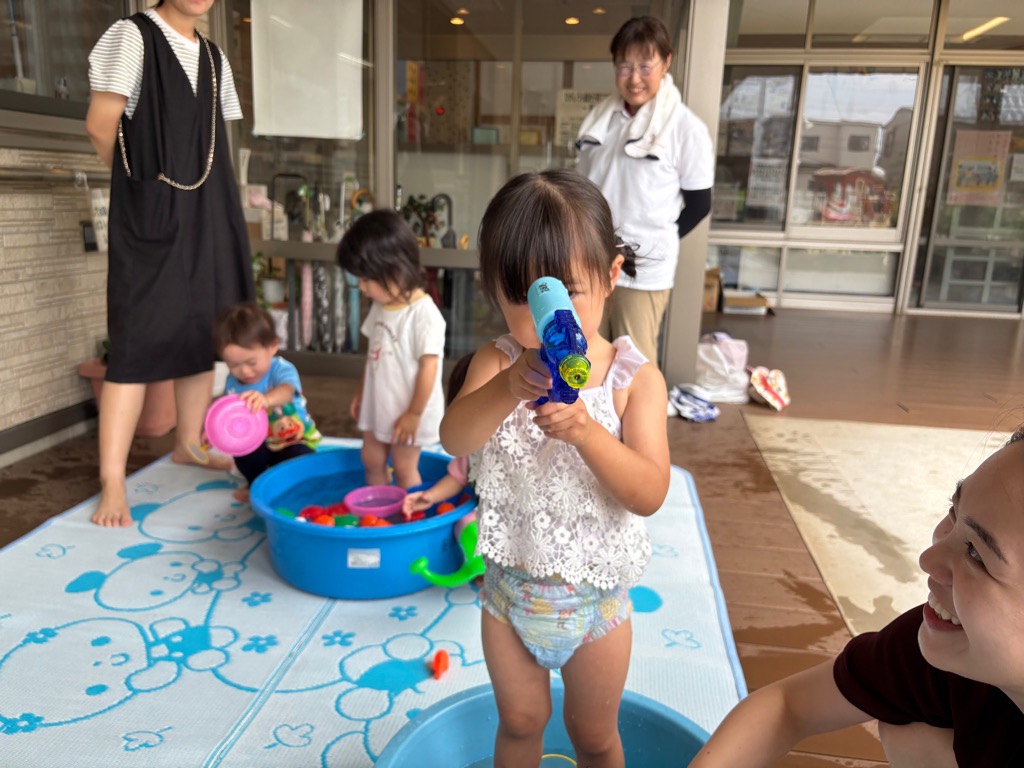 女の子が水鉄砲で水をかけようとしているところ