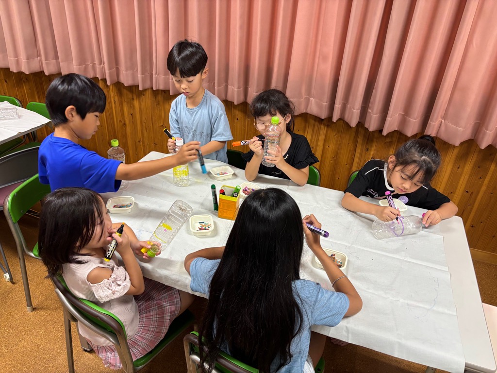 子どもたちがペットボトルにマジックで色を塗ったり絵を描いてのランタンづくりをしているところ