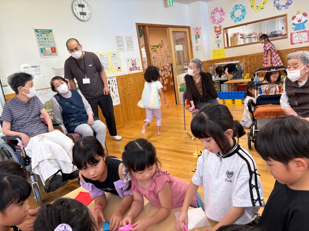 老人ホーム敬愛苑のおばあちゃんにプレゼントする折り紙を折っている女の子たち