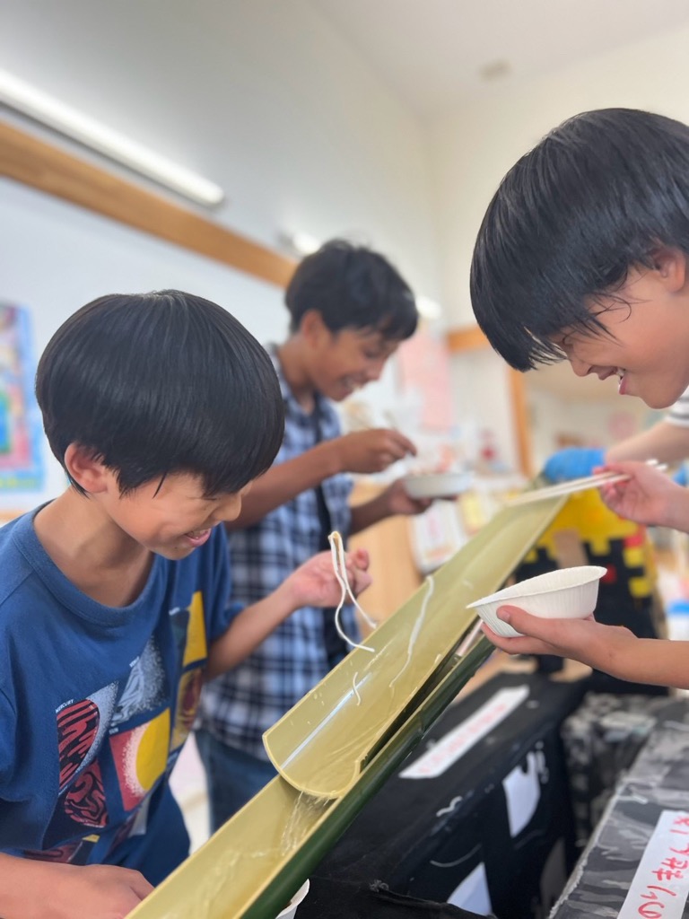 流れるそうめんをつかもうとしたら一本しかつかめず笑っている男の子たち