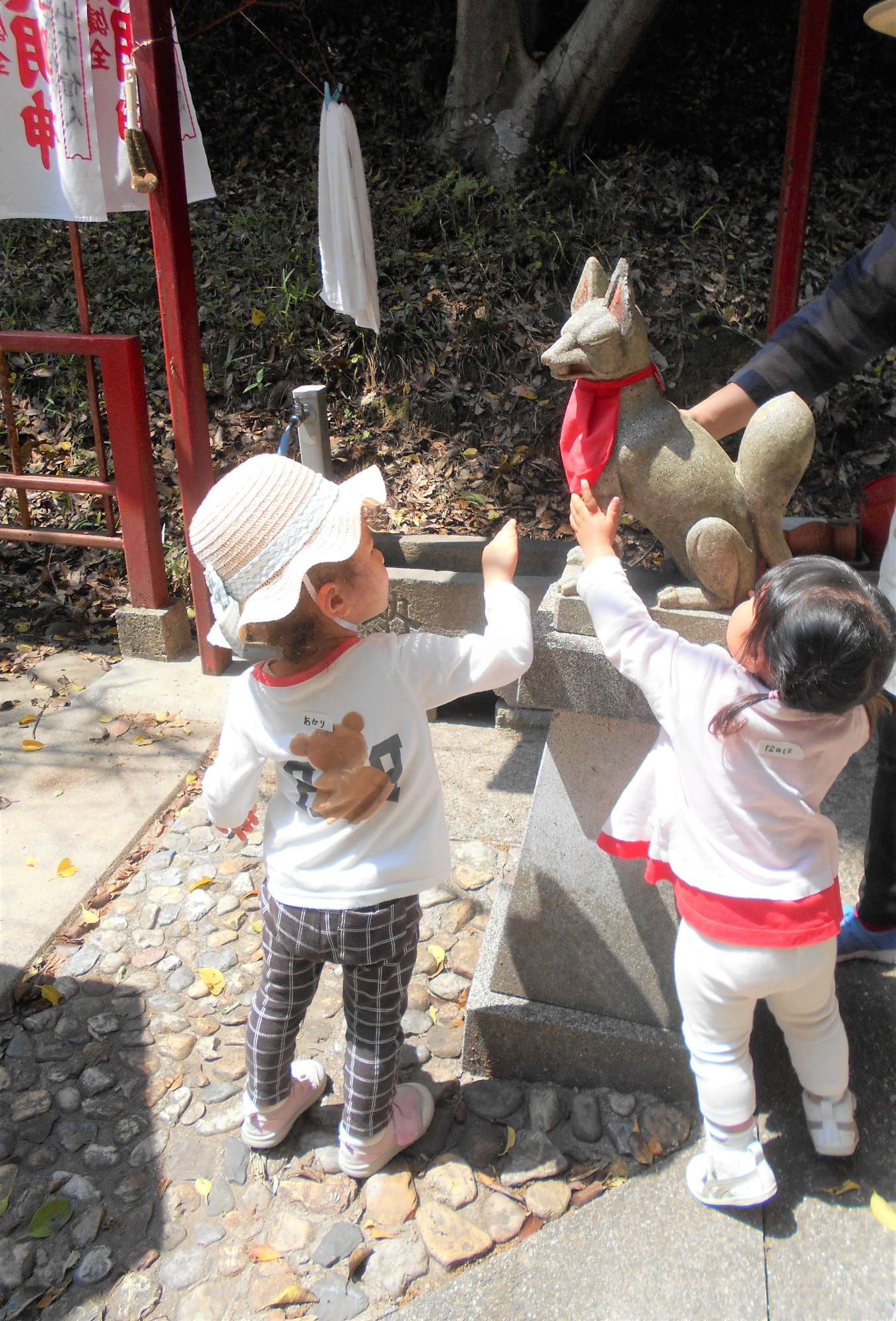 子どもたちが白雪神社にて、狛犬を撫でている