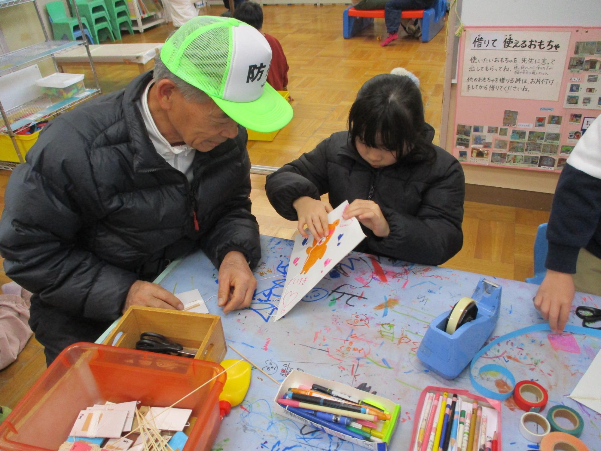 地域の方に教えてもらいながら凧を作るこども