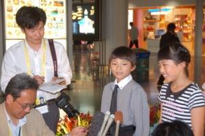 伊勢志摩サミットで花束贈呈役をする藤江小の児童二人が記者達からインタビューを受けている写真