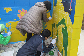 壁画を描く生徒と地域住民