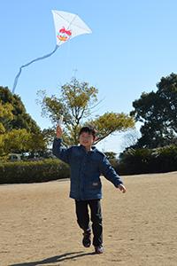凧を片手に走り回る男子児童