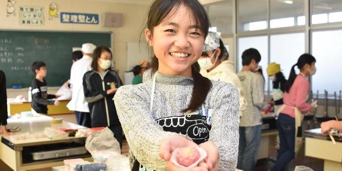 笑顔で完成した和菓子を見せる児童