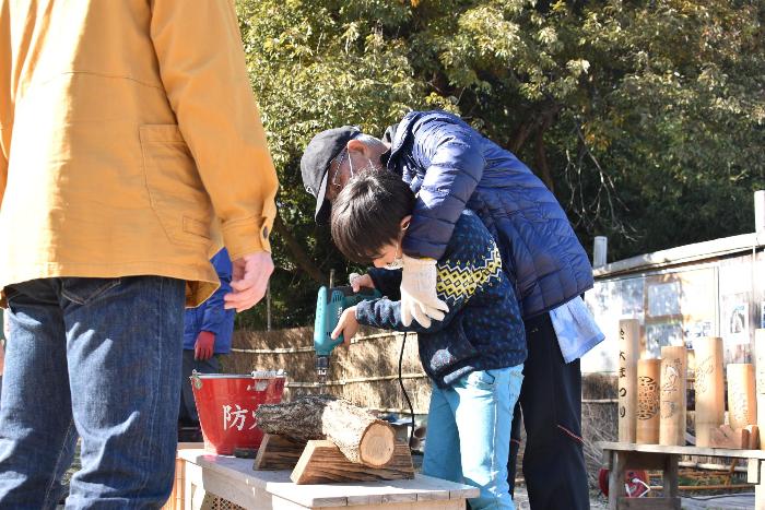 木に穴をあけるためにドリルを使う子ども