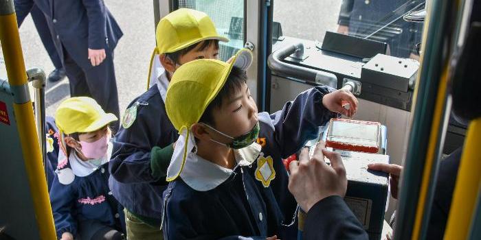 運賃箱にお金を入れる練習をする園児