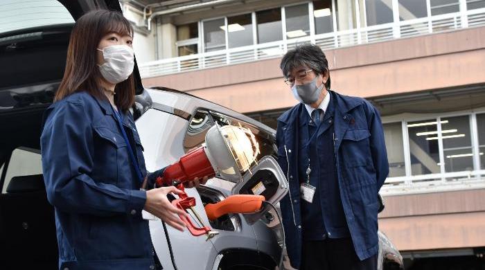 電気自動車から電力がどのように供給されるかを説明する職員