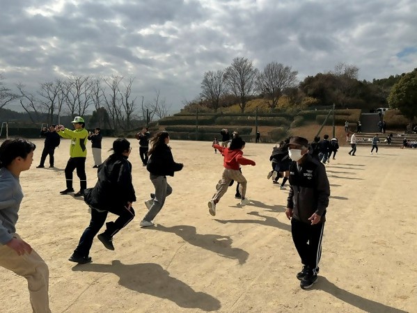 森岡コミュニティの凧あげ大会で大凧を揚げるため糸をもって一生懸命に走る子どもたち