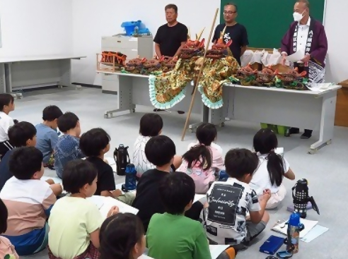 八つ頭保存会の方から「だんつく」について学ぶ3年生の子どもたち