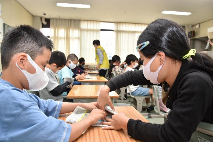 新聞紙でスリッパを作成する様子