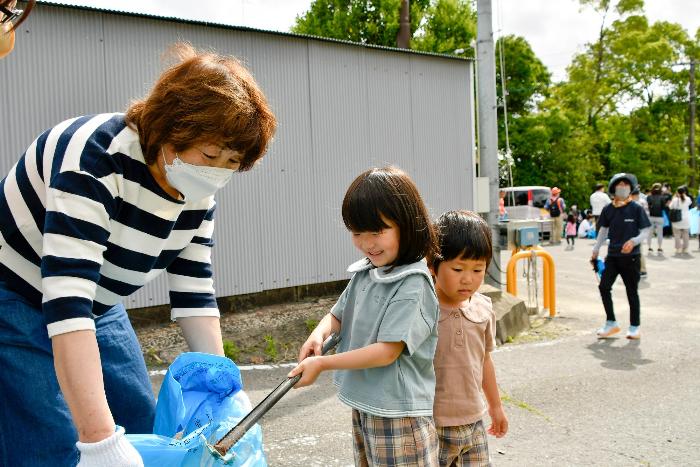 ごみをトングで拾い、ごみ袋に入れる子ども