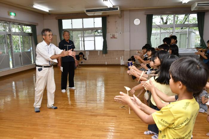 竹とんぼの飛ばし方を児童に教える様子