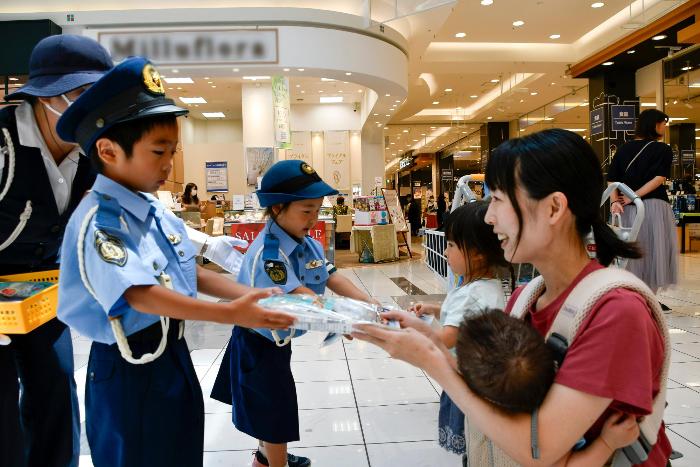 啓発品を手渡すちびっこ警官