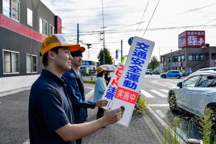 交通安全のプレートを掲げて啓発する職員