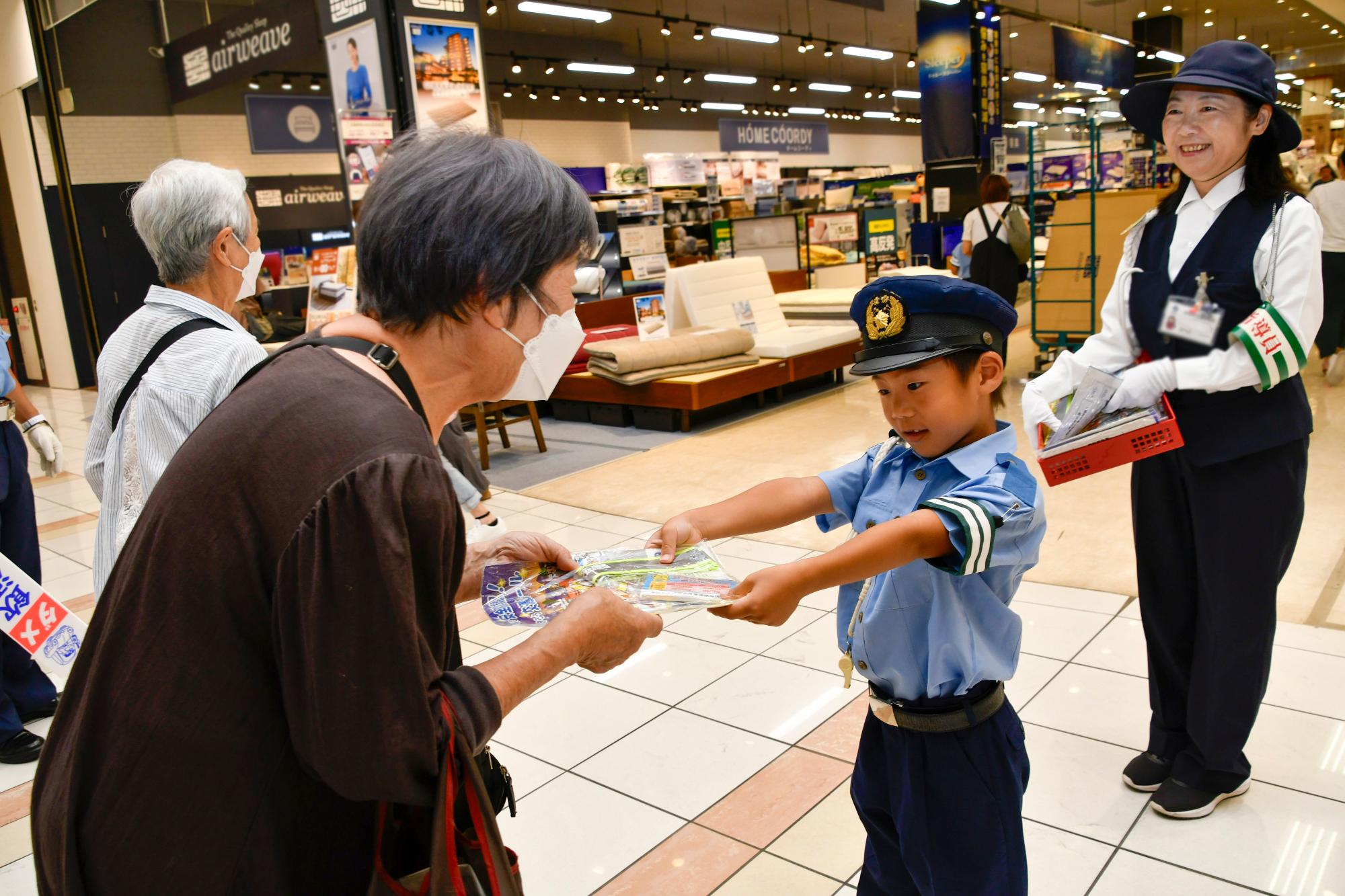 啓発品を手渡すちびっこ警官