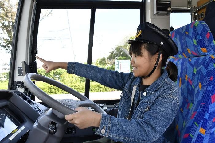 うららの運転席に座って出発のポーズをする児童