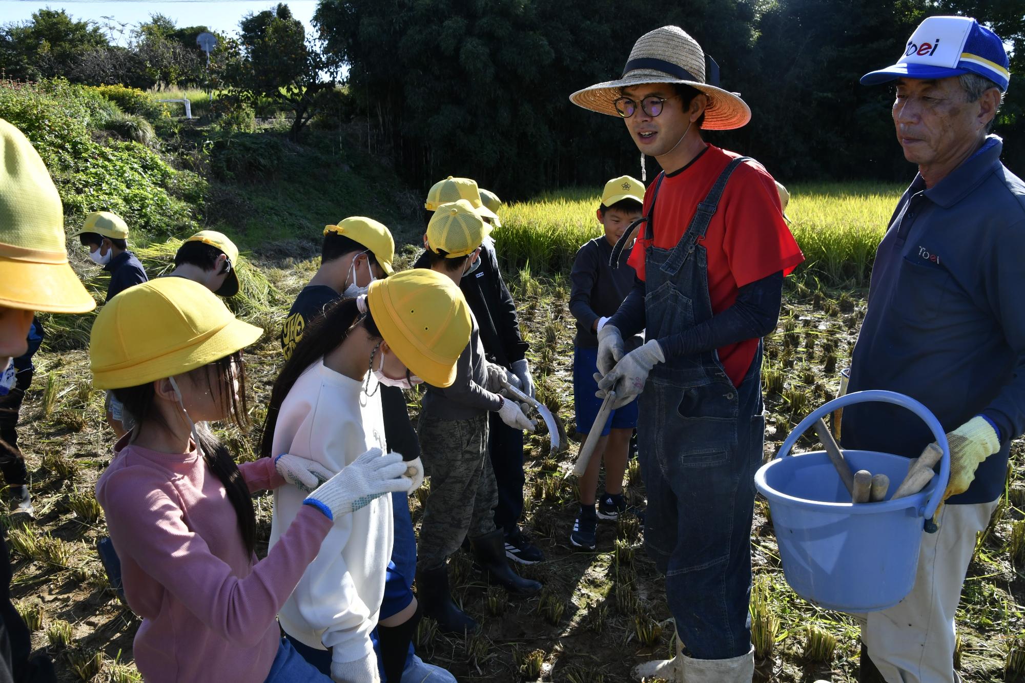 たかしマンから鎌を受け取る児童