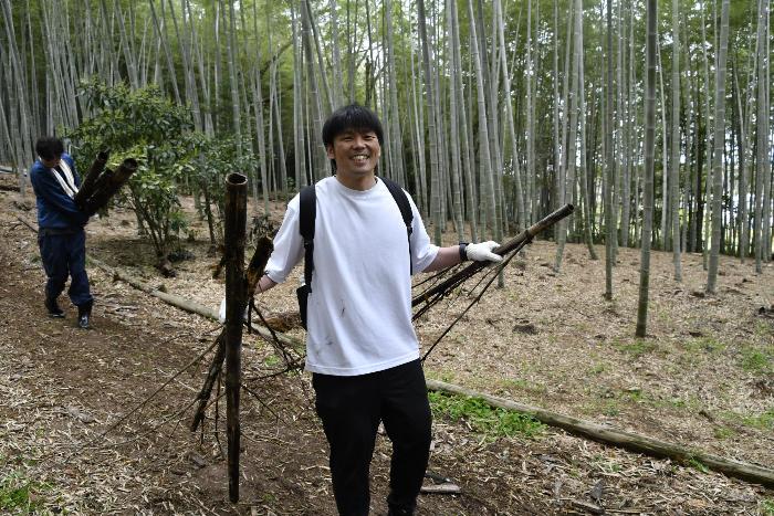 両手にたけを持ち運搬する参加者