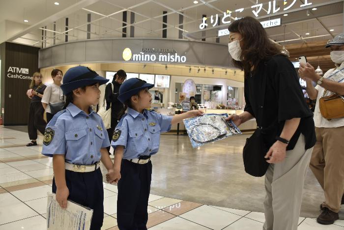 啓発品を手渡しするちびっこ警官二人